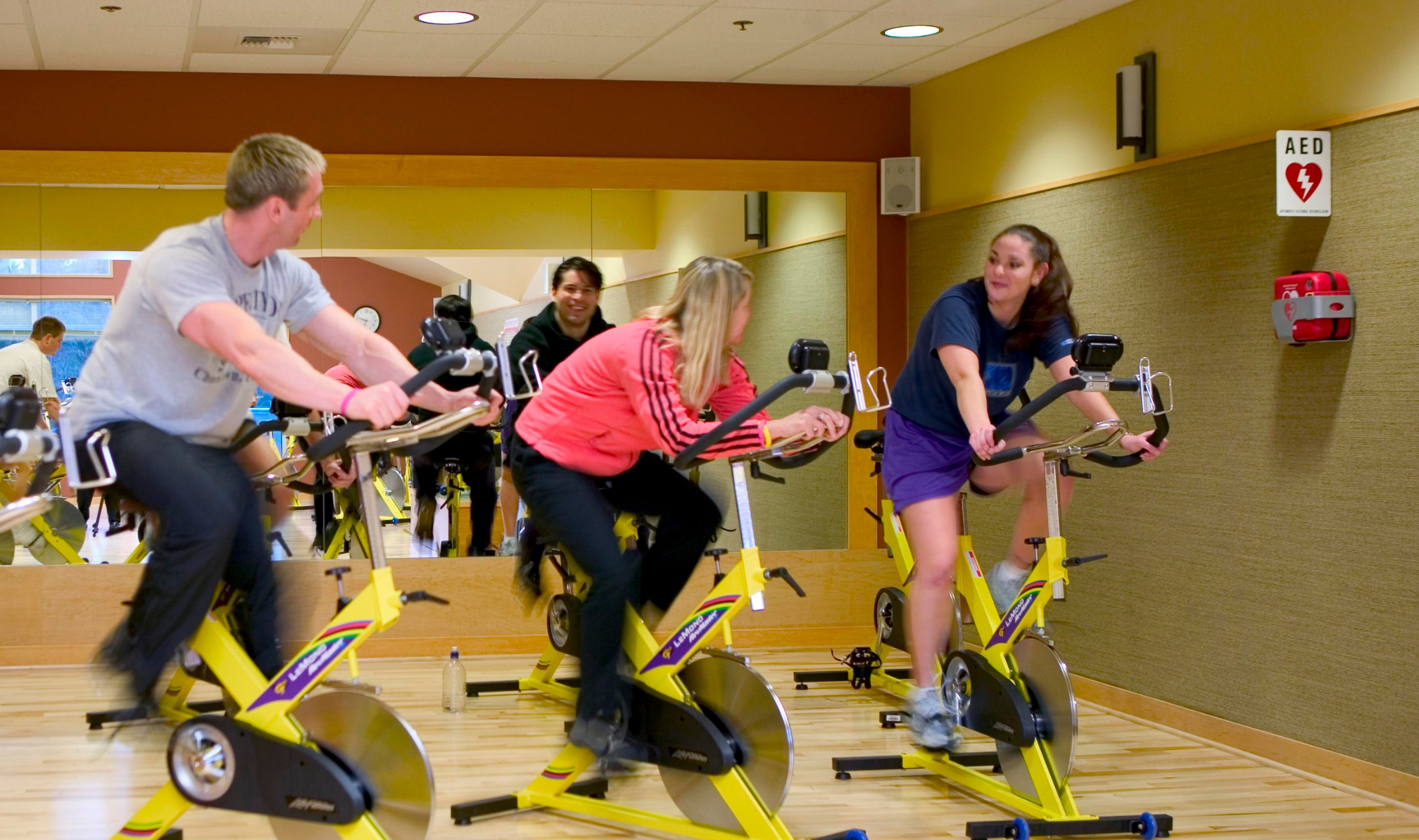 Personne faisant du sport dans une salle de sport où il y a un défibrillateur